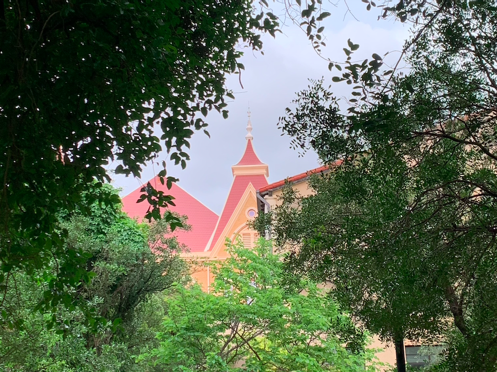 the peak of old main seen through trees at texas state university