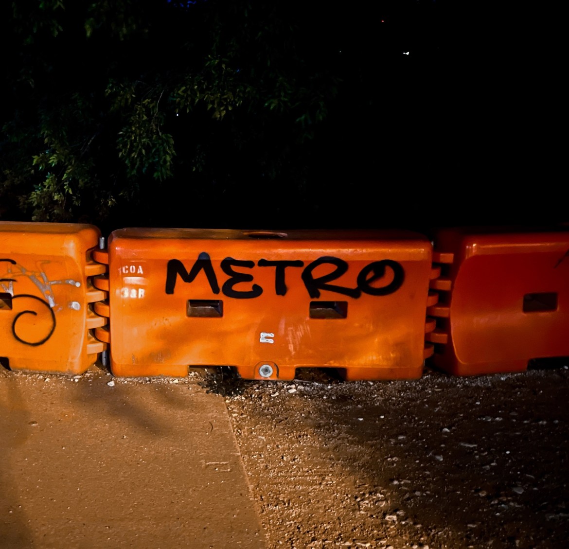 The word ‘Metro’ spray painting on an orange wall in a dark park. Referencing Metro’s name being “everywhere”