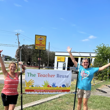 Two people standing next to a banner that says "the teacher reuse"