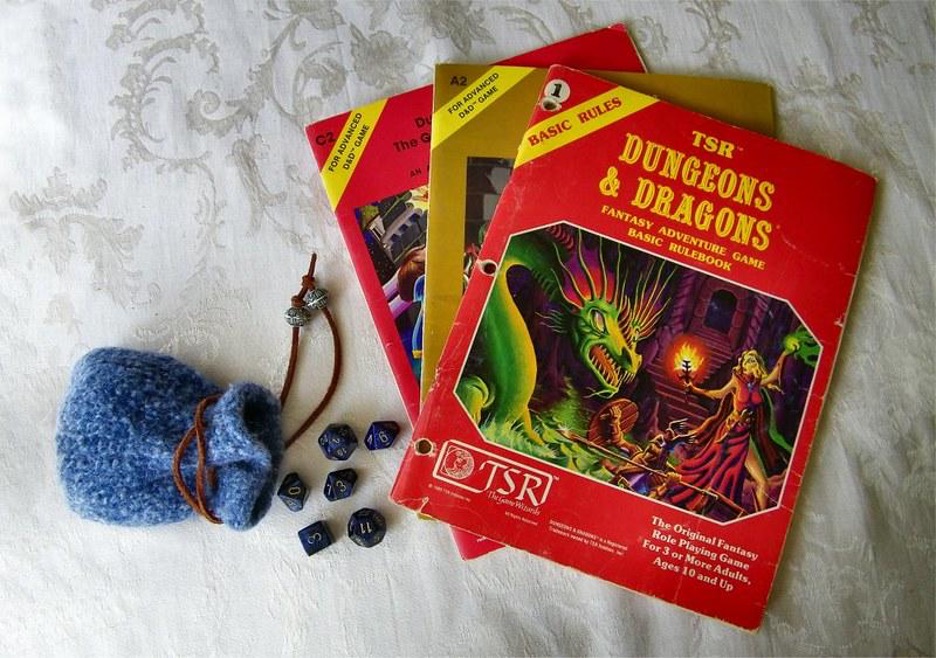 A photo of a pouch of dice lying alongside a set of three red Dungeons and Dragons books.