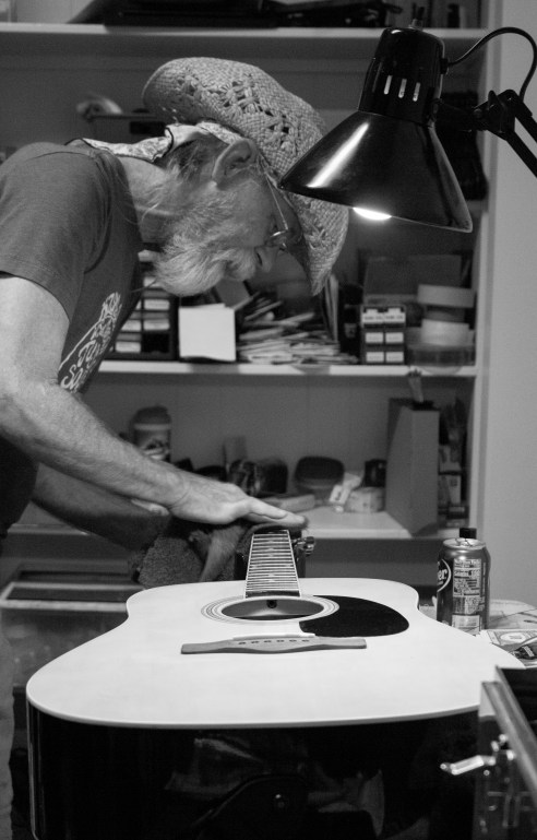 Ace fixing up a guitar in black and white.