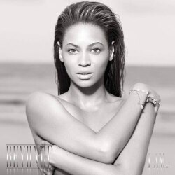 A black and white photo of Beyonce with her arms covering her breasts. A body of water is out of focus in the background.