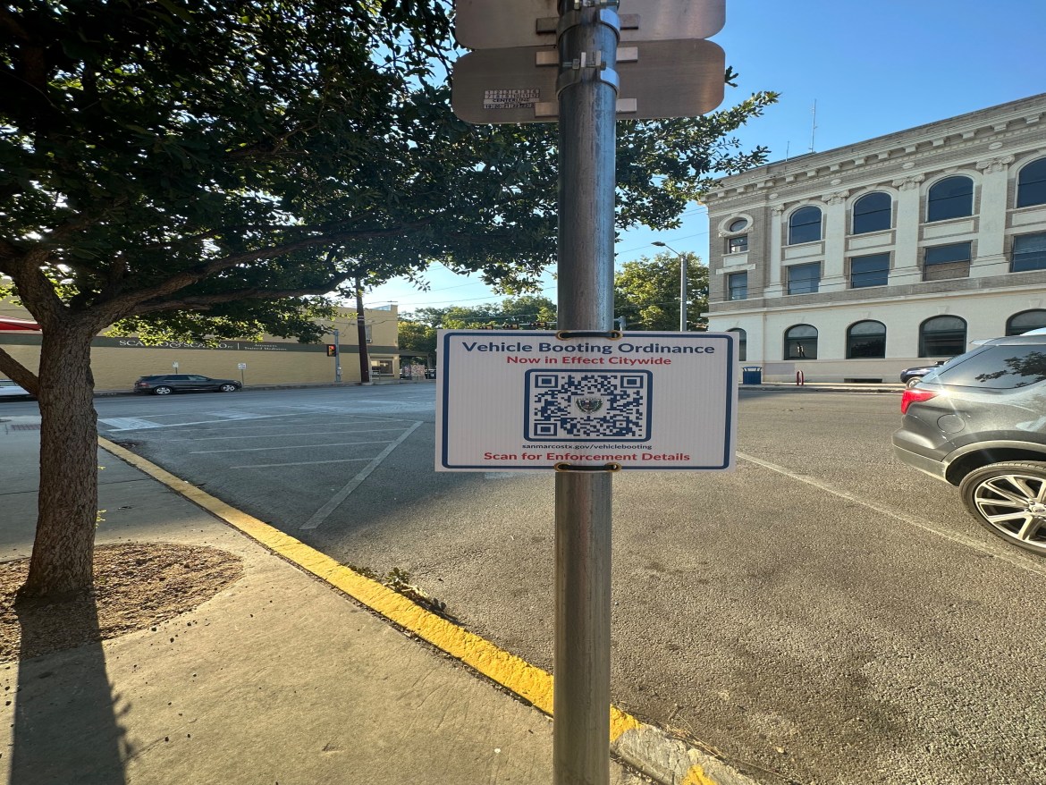 A sign on the square with a QR code for more information on the booting ordinance.