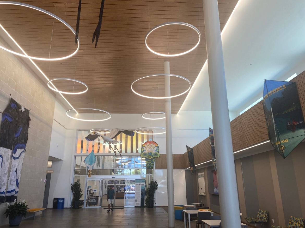 Circular overhead lights illuminate a foyer with various kites