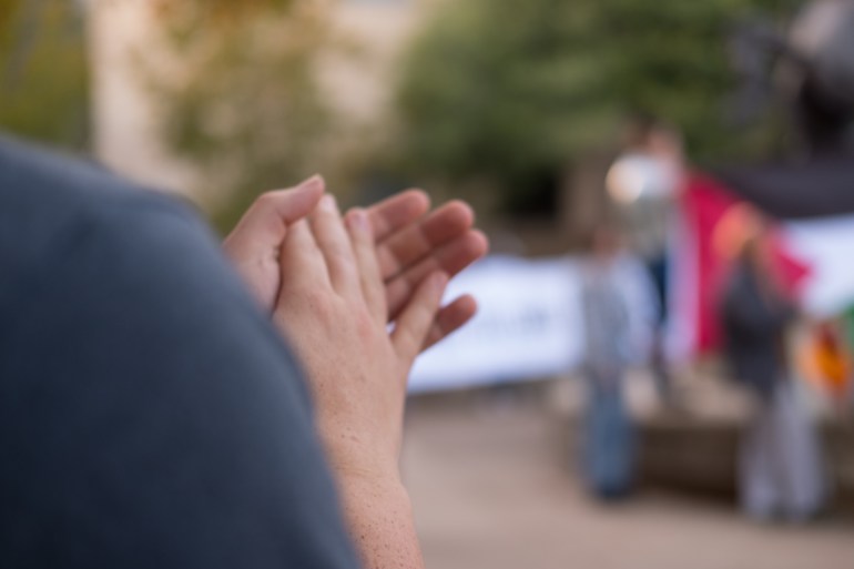 a close up of hands clapping at a Palestine Solidarity SMTX peaceful protest at Texas State University near stallions statue