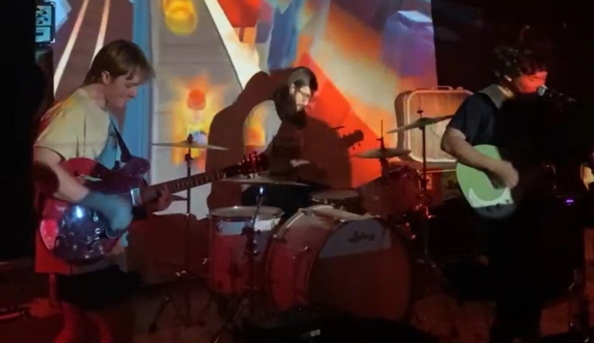 The image shows the band April Company playing at a music venue in Austin called The Inner Chamber.