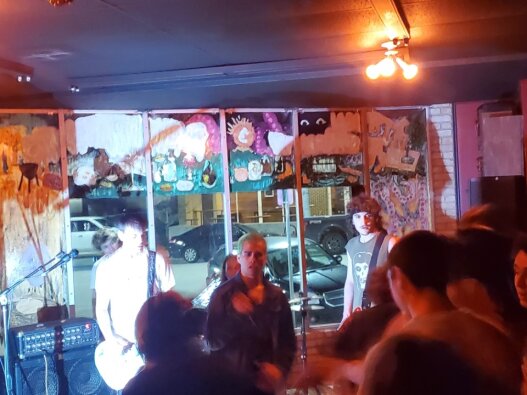 : Camera flash lights up the stage for the punk band, Asbestosis, at February concert at Alchemy Records. 