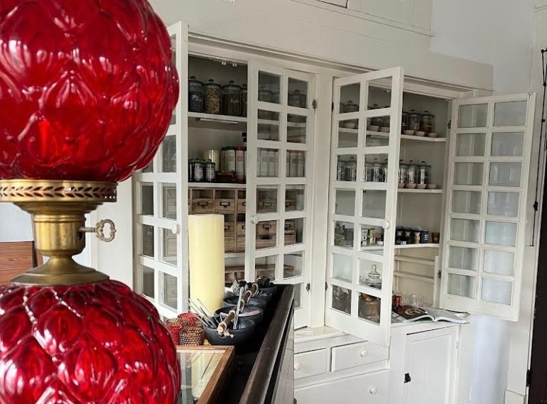 A red lamp sits on the edge of the check-out counter peering over to built-in shelves. 