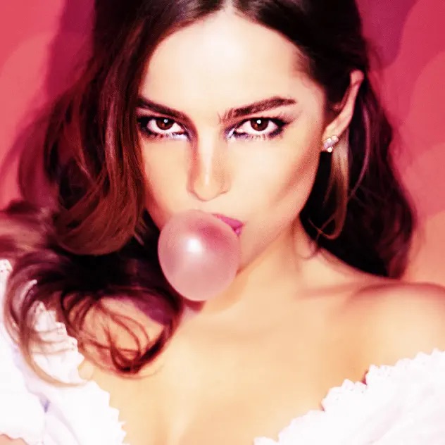 Addison Rae blowing a gum bubble on a pink background