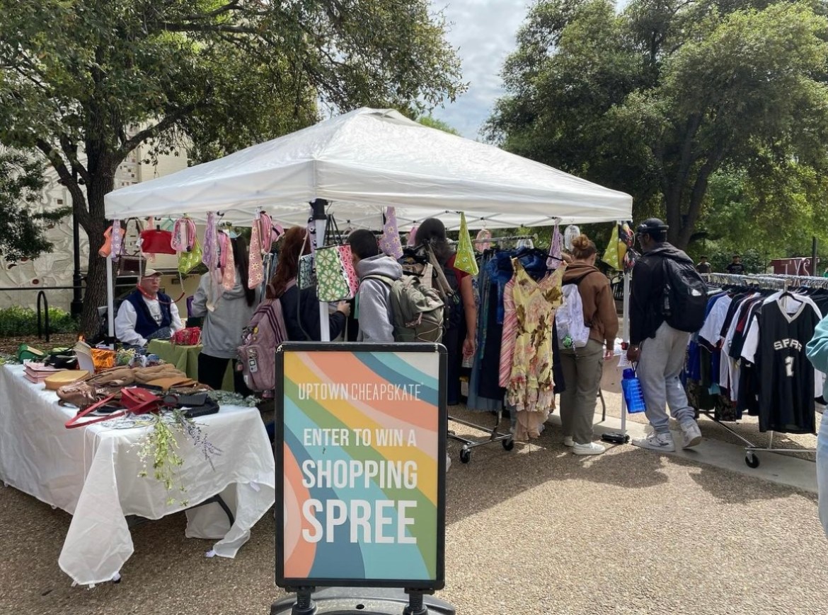 : A sign to enter a shopping spree giveaway with a tabling setup behind the sign at market day on the quad.