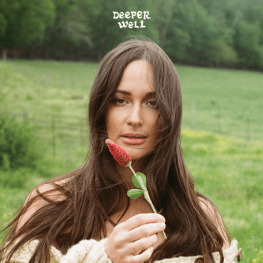 : Kacey Musgraves holding a red plant in a field