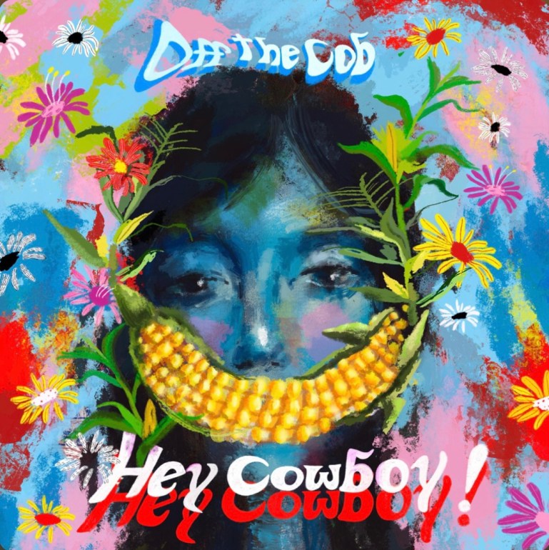 The Album cover of “Hey Cowboy!” A colorful portrait of a blue female with a corn on the cob smile, with the captions “Off the Cob” and “Hey Cowboy!”