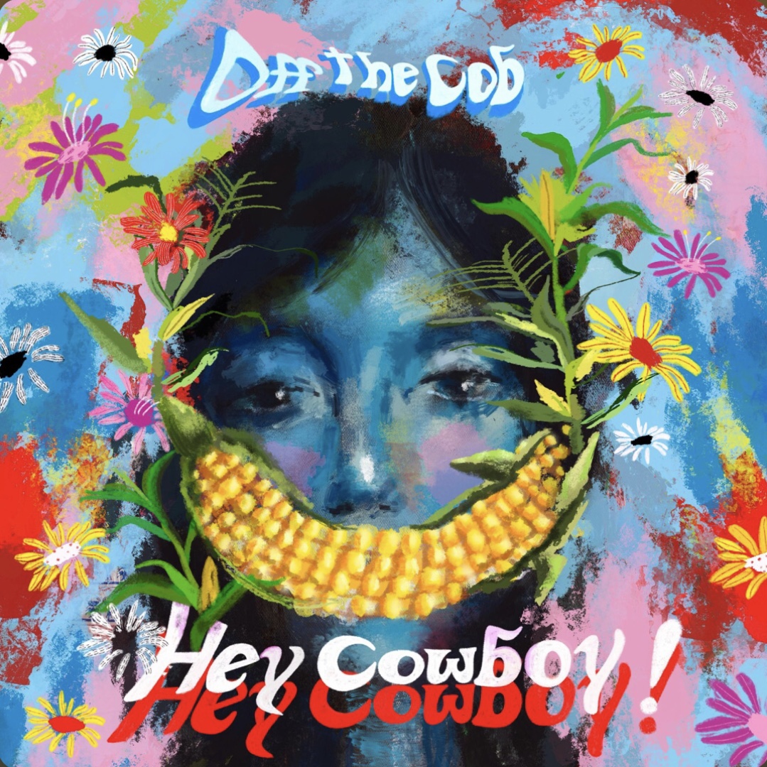 The Album cover of “Hey Cowboy!” A colorful portrait of a blue female with a corn on the cob smile, with the captions “Off the Cob” and “Hey Cowboy!”
