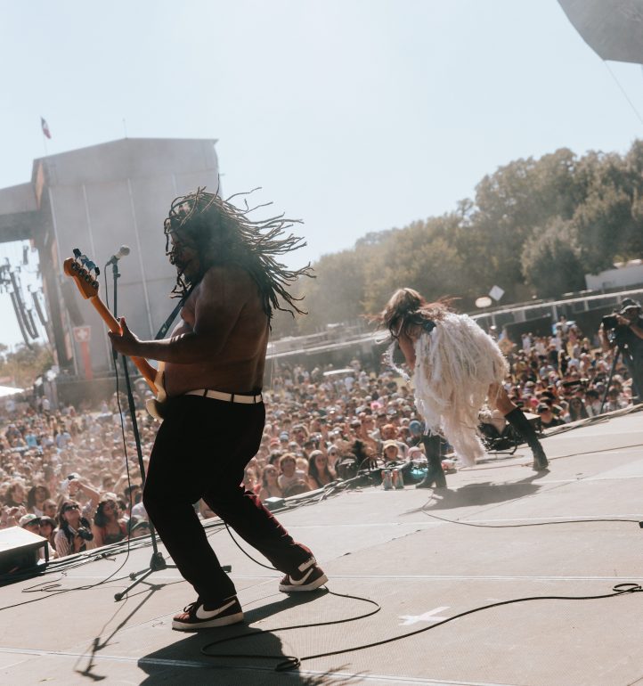 two band mambers, (right) playing guitar, (left) singing to the crowd