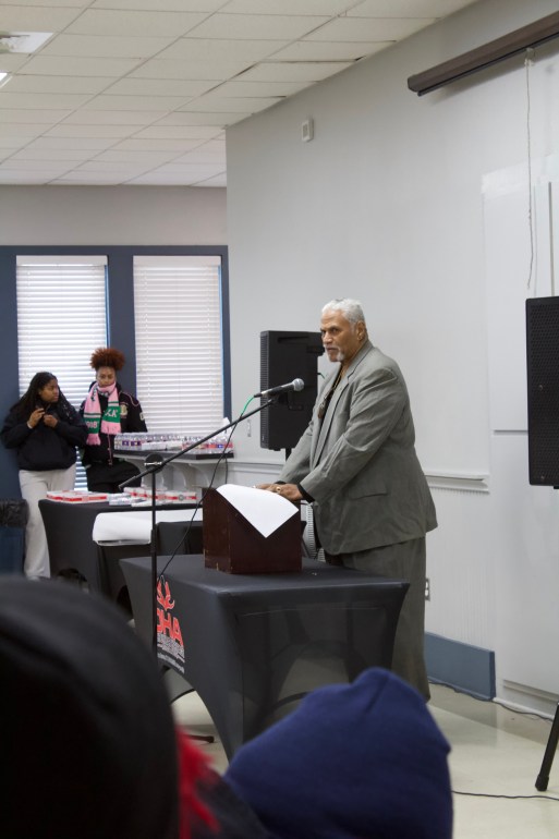 Ralph Merriweather stands at a podium at the center of the room to give a keynote speech. 