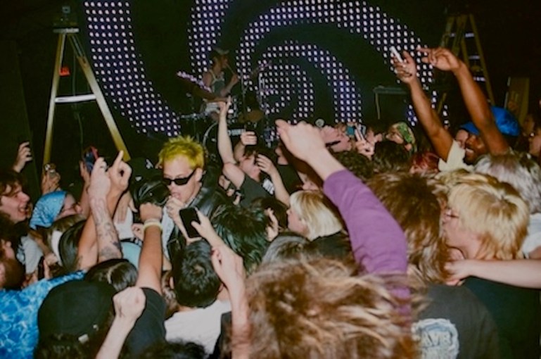 Top down shot of the crowd facing the stage with George Clanton (middle left) drowning in the waves of hands after jumping into the crowd to mosh during one of his songs.