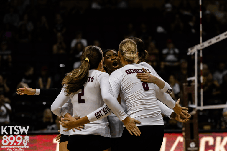 Texas State volleyball players celebrate in a huddle during a match.