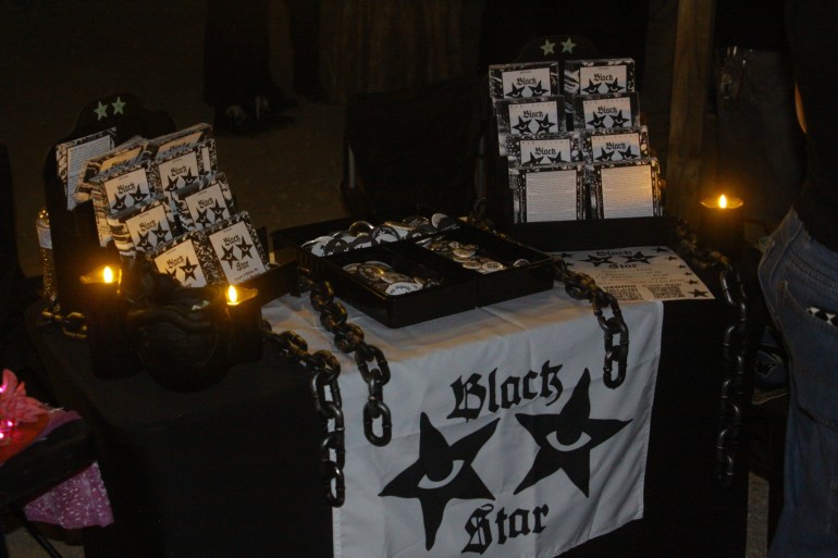 A booth decorated with chains and a cloth set up with dozens of zines to giveaway to concertgoers.