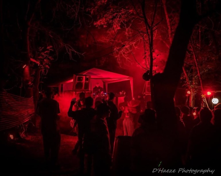 Attendees enjoying a nighttime set with complete red lighting in the forest.