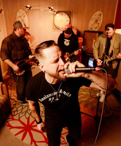 Kill Verona’s lead singer in the center of the camera lens while the other three bandmates surround him,