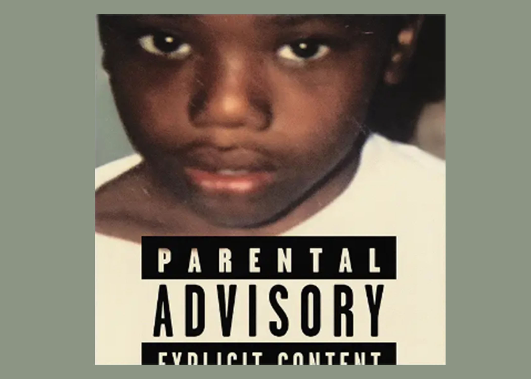 Close-up photo of a young boy in a white t-shirt with a large parental advisory warning pasted over the front of his shirt.