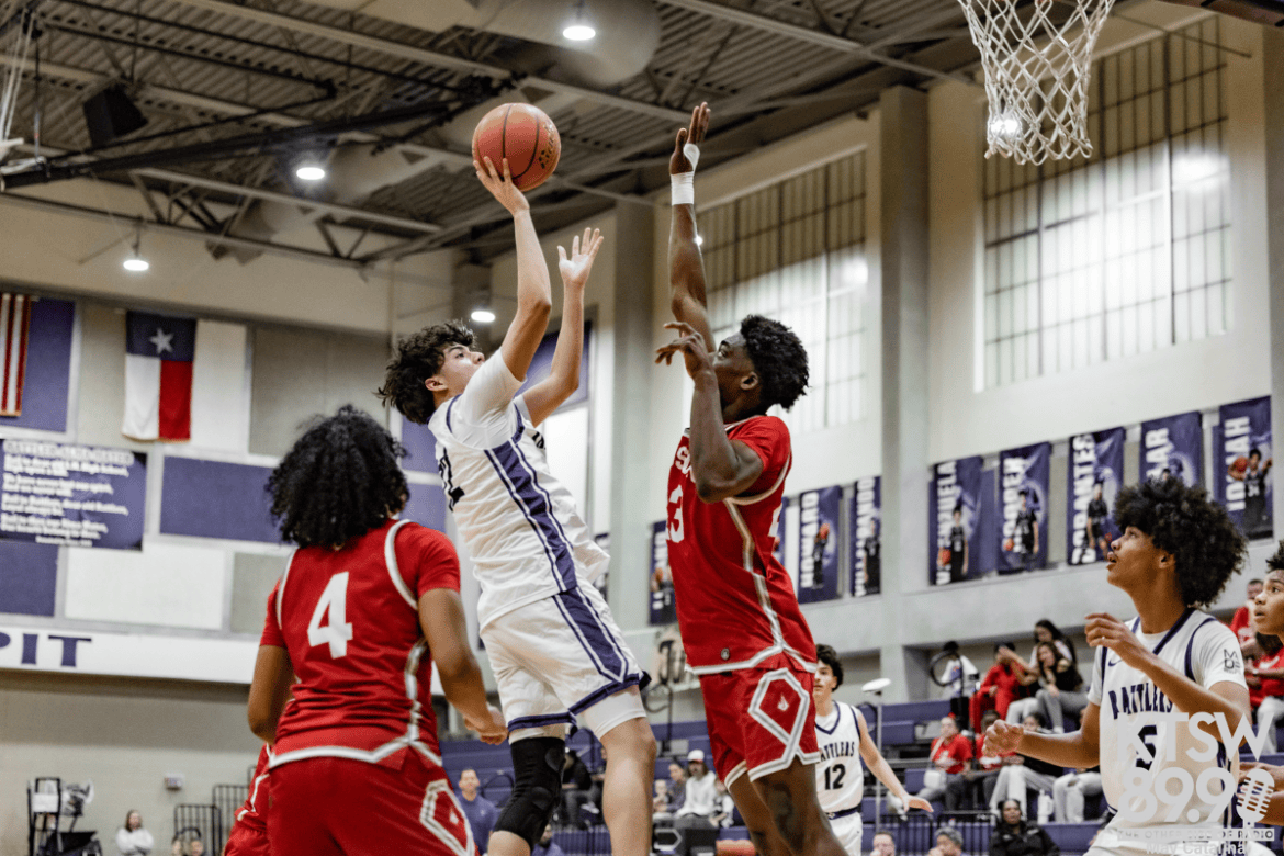 A San Marcos High School player jumps to shoot the ball over defenders.