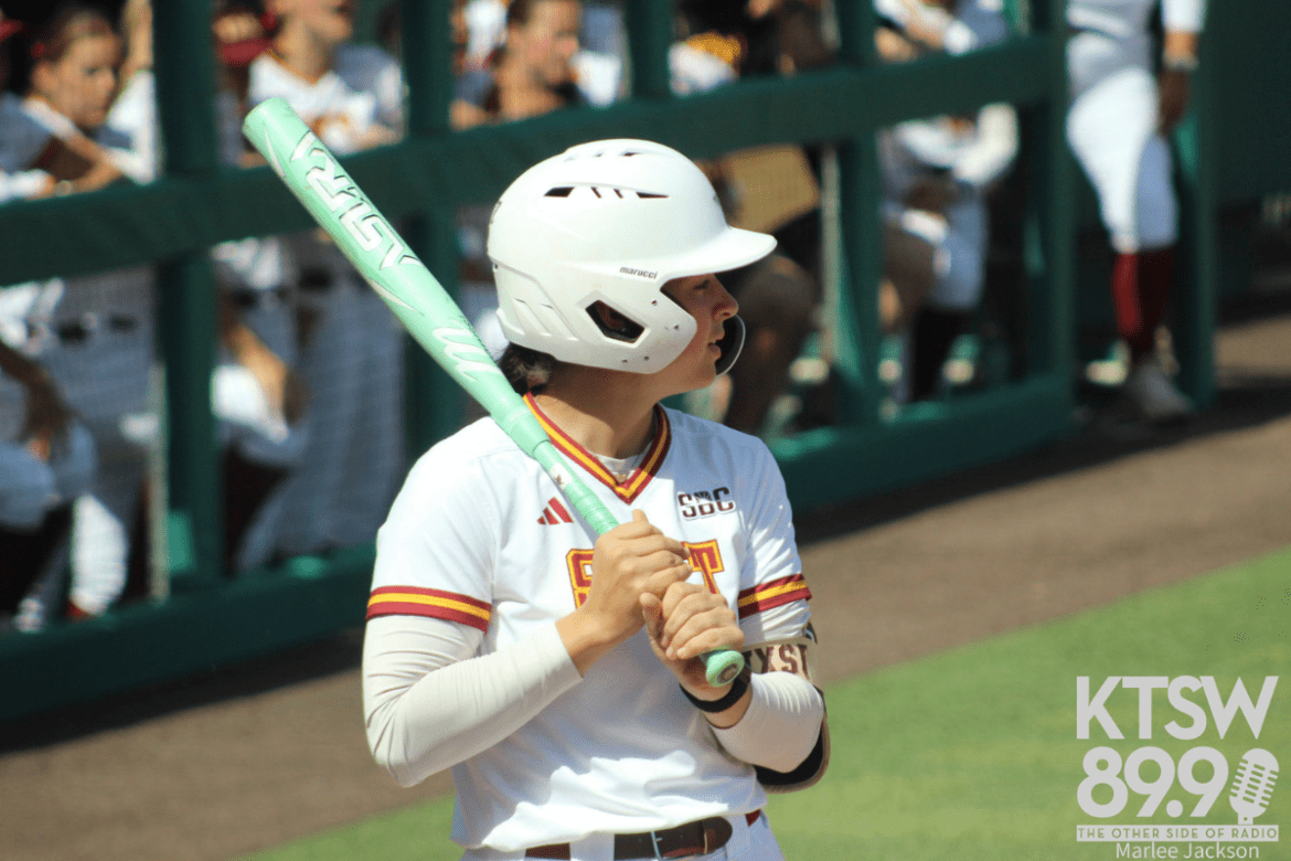 A Texas State player wearing a throwback "SWT" jersey is seen warming up with her bat over her shoulder.