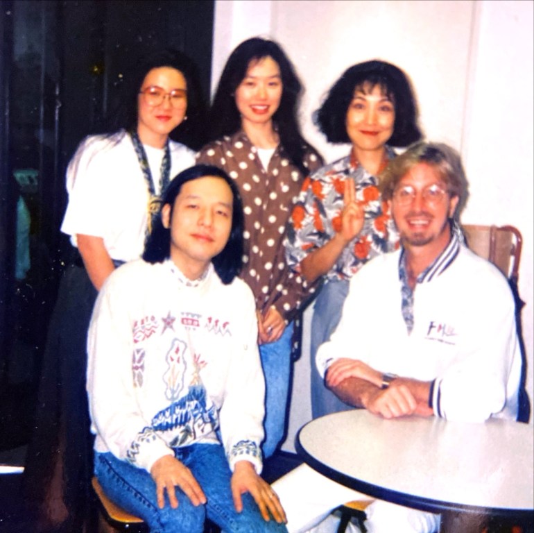 Old family picture of 5 people, 2 sitting down, and smiling