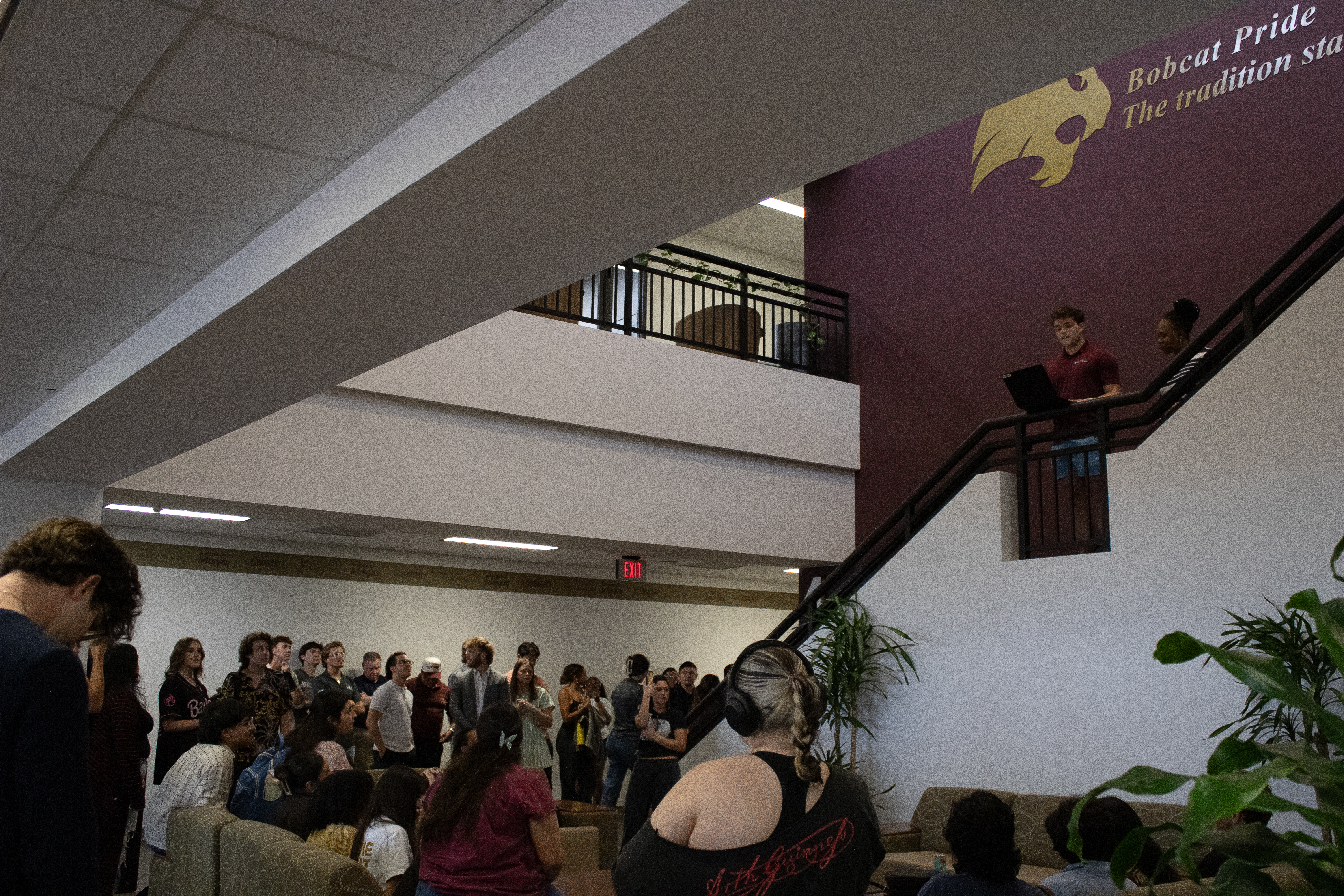 Students gathered in a crowd at the bottom of the stairs, with an announcer on the stairs with a computer and the results.