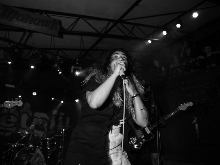Black and white image of lead singer Zayna of Sweet Pill with a menacing stare at the crowd while singing