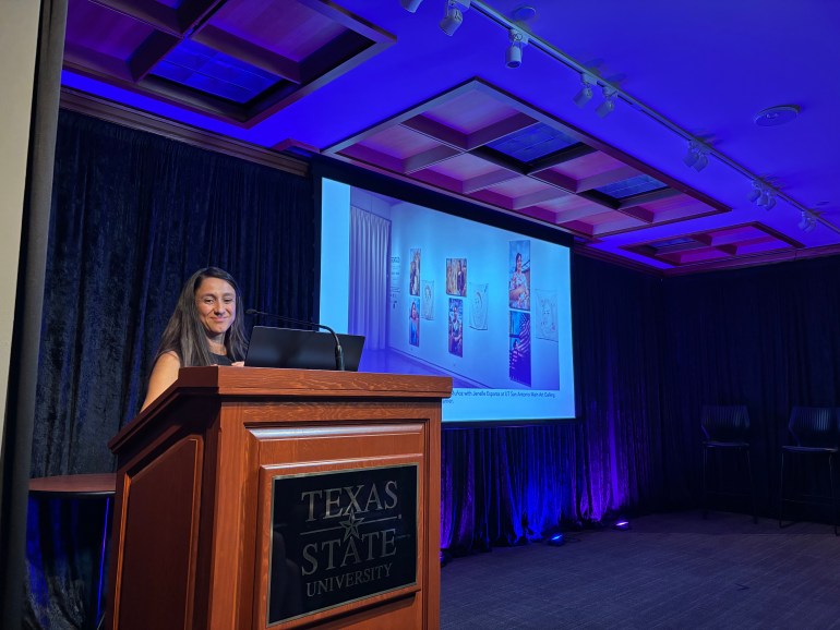 M. Jenea Sánchez stands at a Texas State podium on the left side, her slidehow presentation featuring her art is displayed on the right. 
