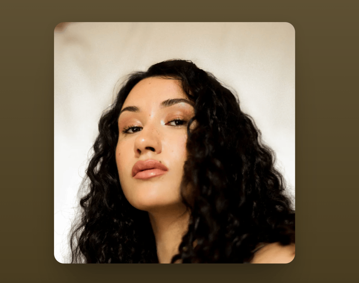 Portrait of Cleo Sol with curly dark hair against a cream and brown background.