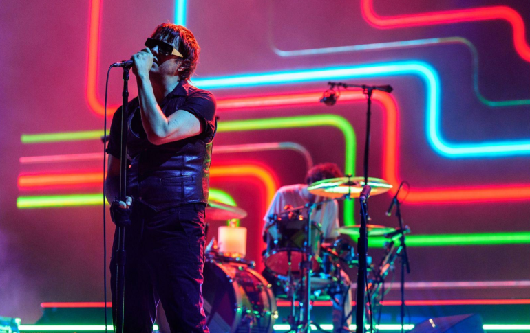Julian Casablancas performing live at Coachella 2026 with neon light signs