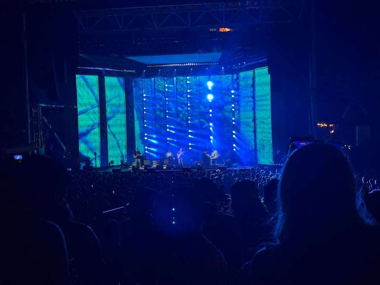 Jack Johnson performing at Germania Insurance Amphitheater on 8/29/26 with blue shining lights and a full crowd of people. 