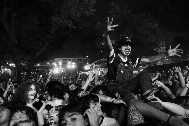 A photo of the packed crowd at Stubbs with a person being held above the crowd in clown-like face paint enjoying the performance.