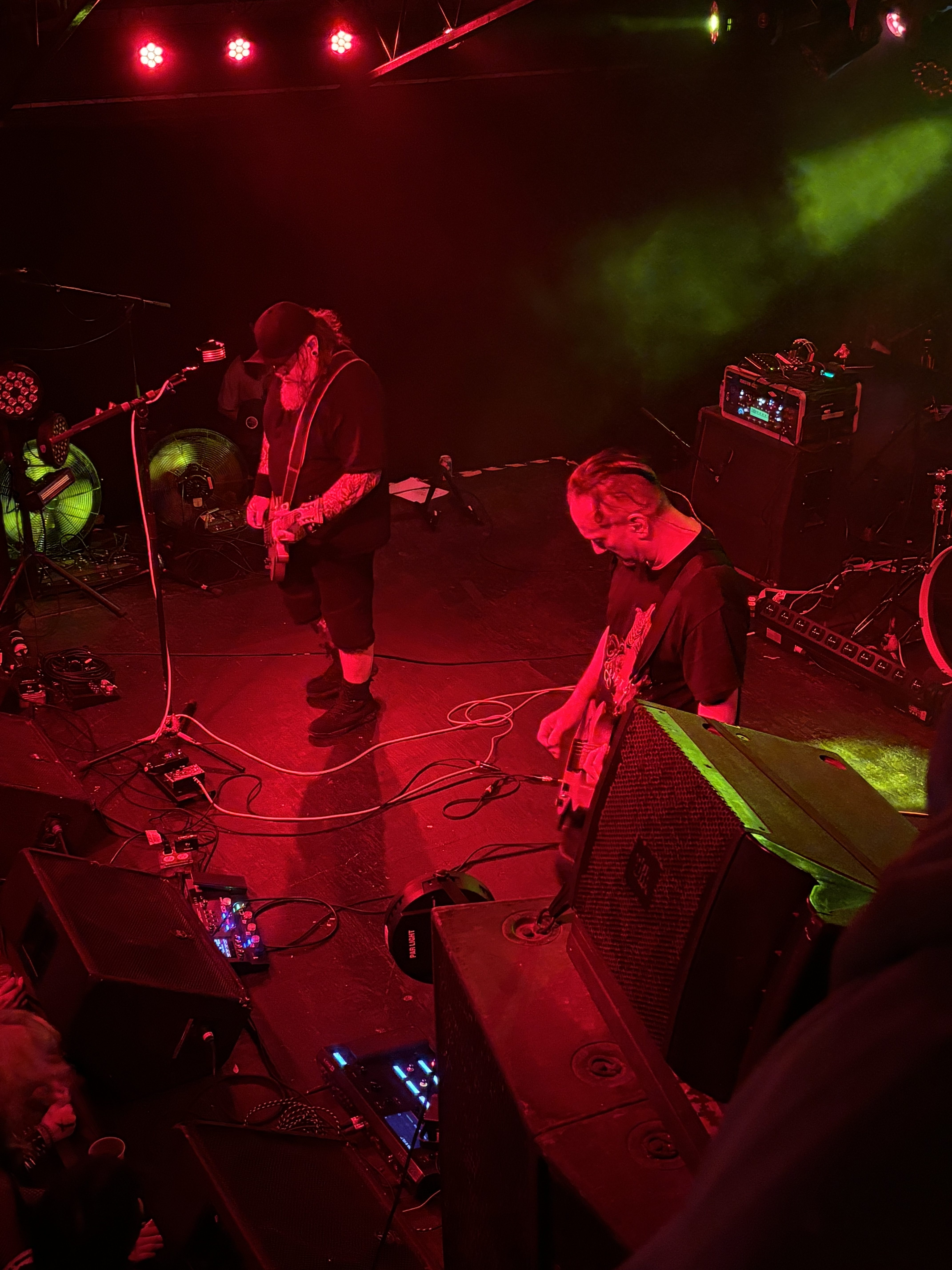 Members of 16volt Eric Powell, frontman and rhythm guitarist on left and lead guitarist, Rick Furr on the right of a red-lit stage.  