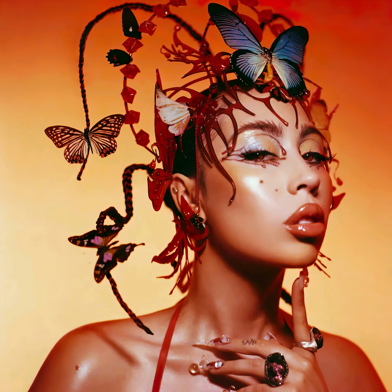 The cover of Kali Uchis Red Moon in Venus album with her having butterflies on her hair as her pointer finger rest her head on it.