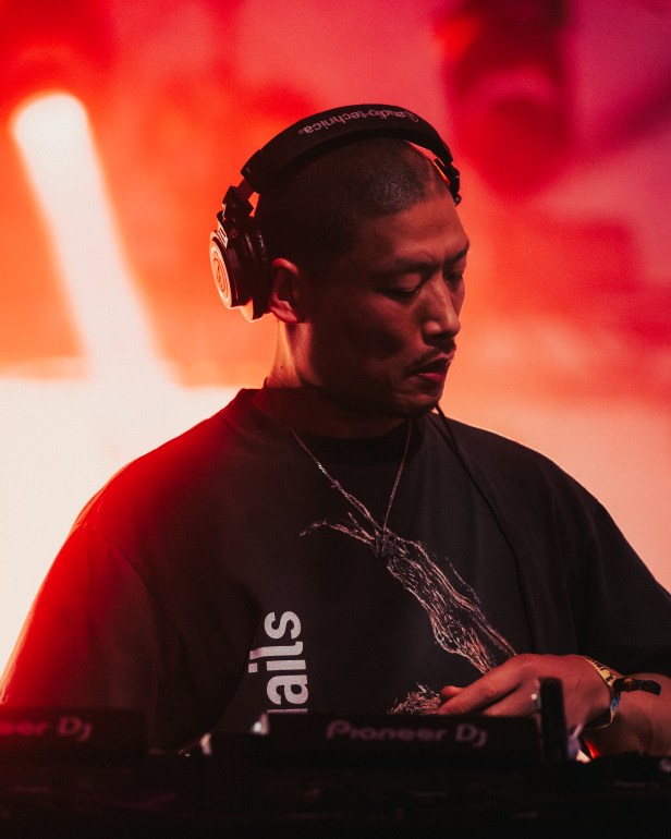 The image depicts a close up of Japanese DJ Yousuke Yukimatsu as he is playing a set at the Tito's Stage.