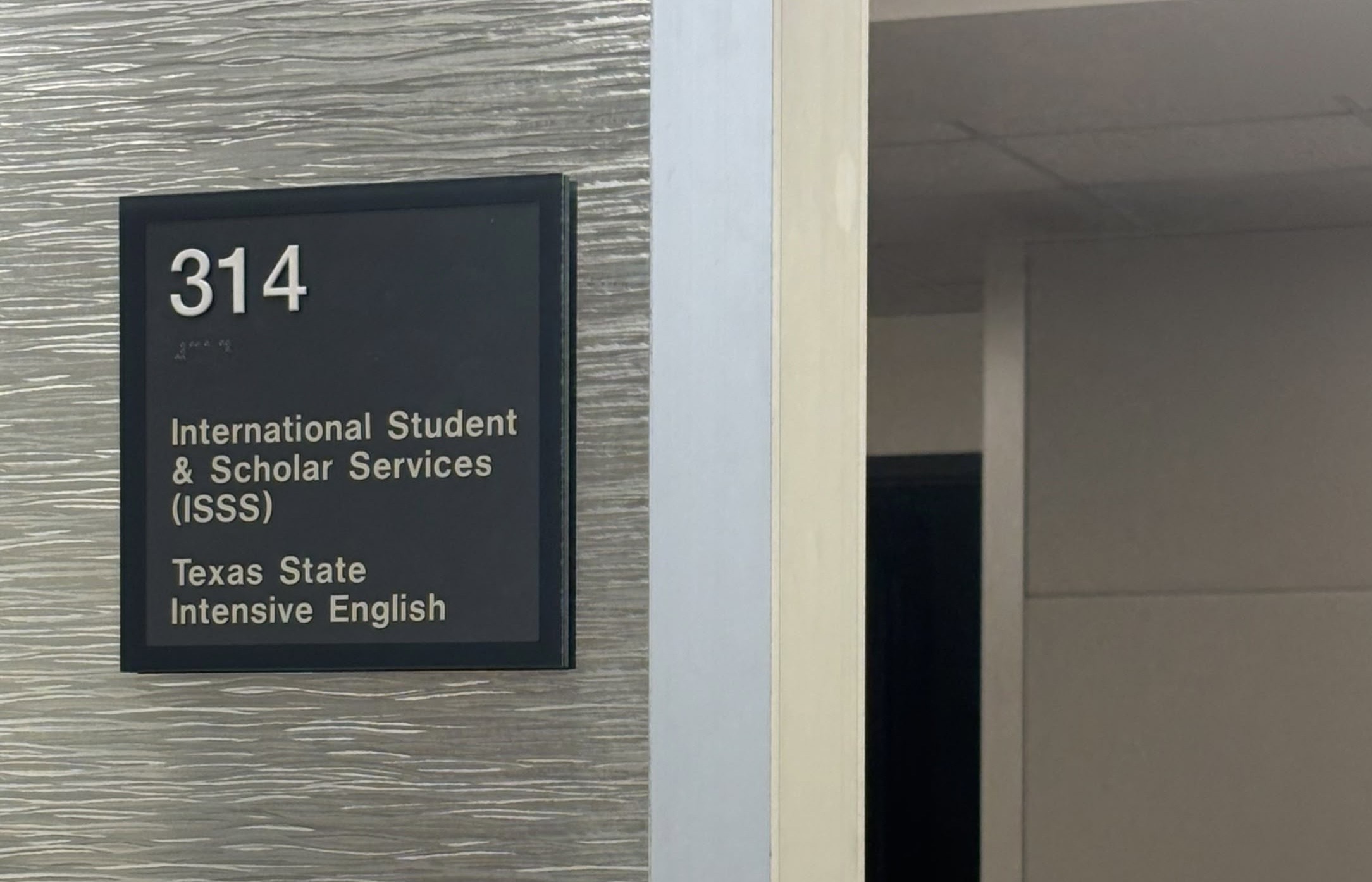 Grey square sign on office door that reads "314, International Student & Scholar Services (ISSS), Texas State Intensive English.